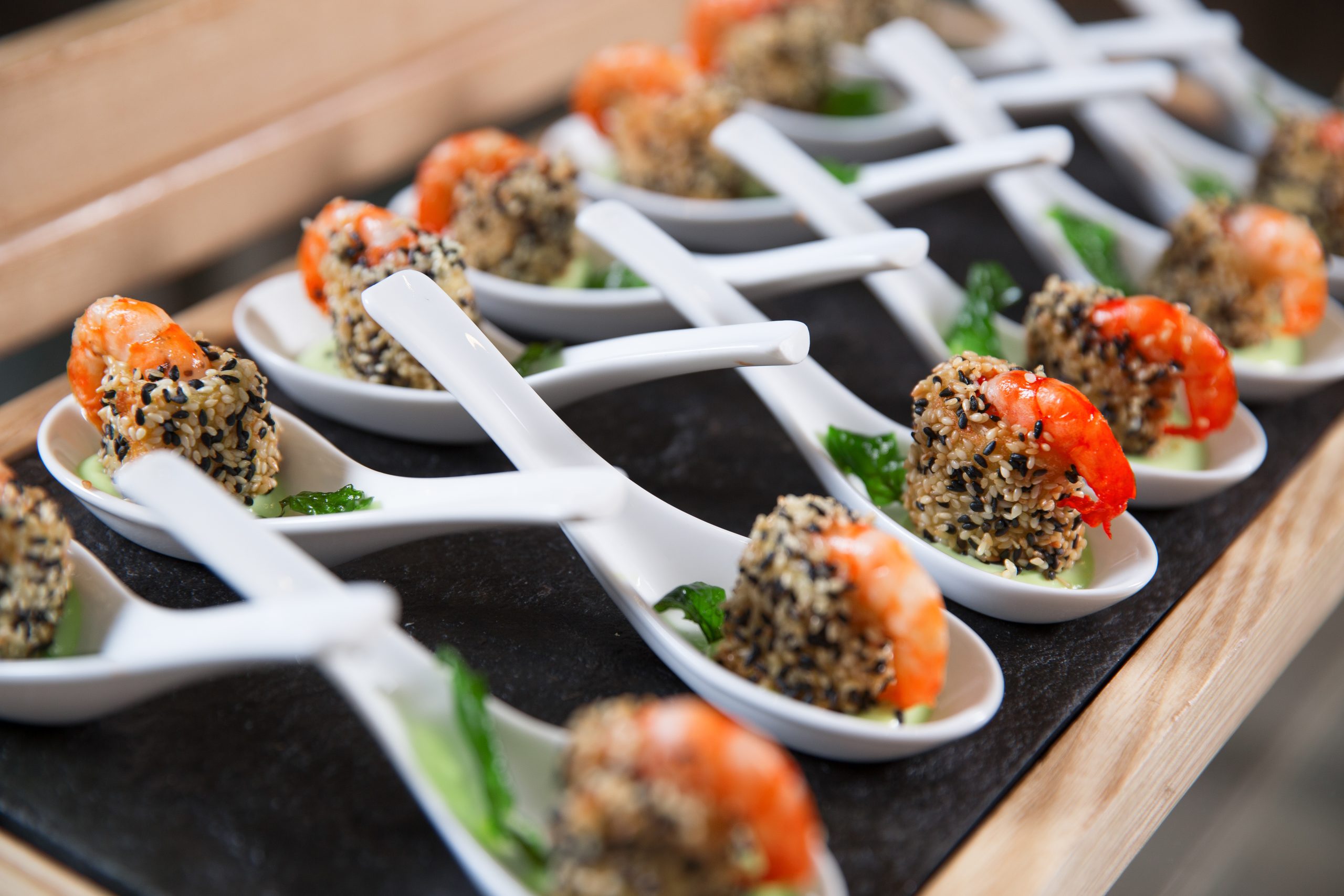 Delicious snacks with shrimps in white little spoons on buffet table. Catering concept